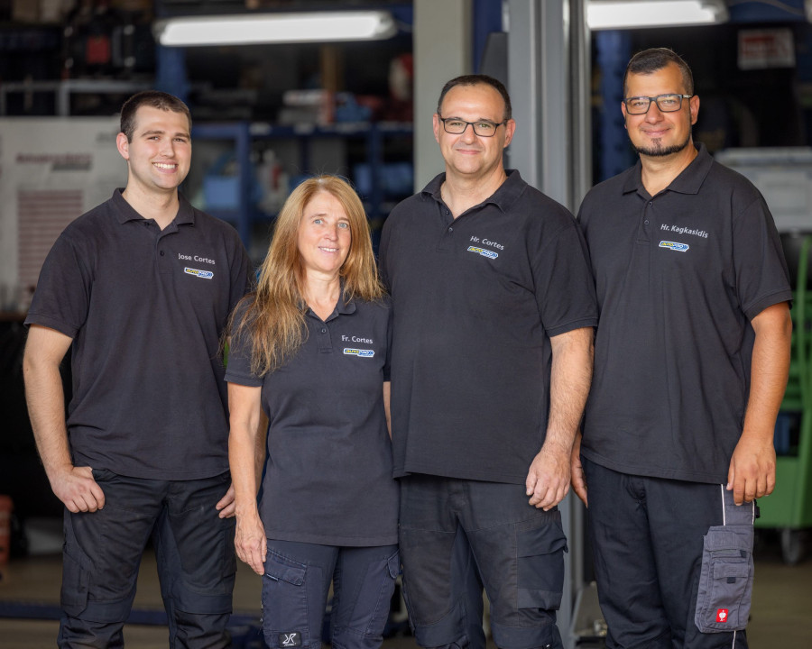 Vierk&ouml;pfiges Werkstattteam in einheitlicher Arbeitskleidung